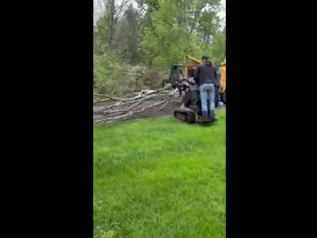 F&B crew feeding limbs into the chipper while the mini loader works the log pile