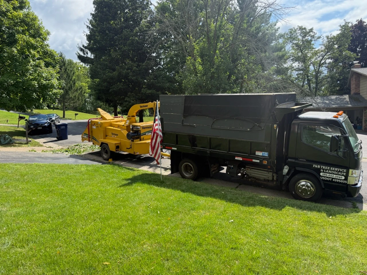 F&B Tree Services dump truck and Vermeer chipper parked in a driveway during a brush cleanup job